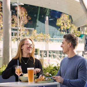 Two guests smiling and eating food at stadium venue