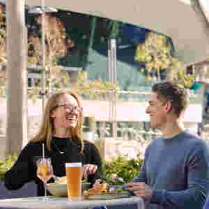 Two guests smiling and eating food at stadium venue