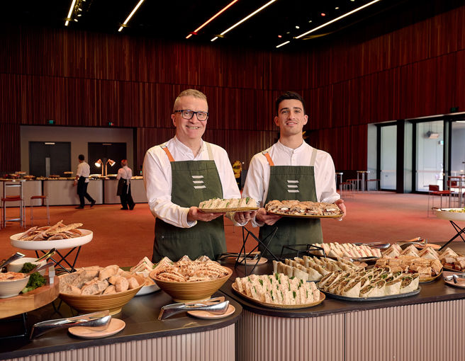 Front of house staff smiling at setting up food buffet for conference