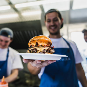 Chef holding out delicious plated burger