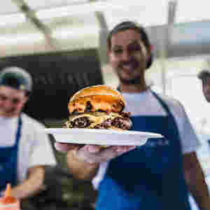 Chef holding out delicious plated burger