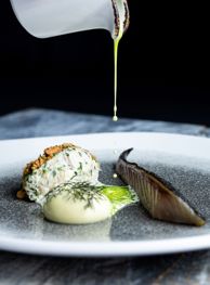 Sauce being poured onto beautifully present premium meal