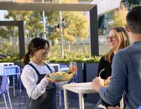 Waitress smiling and delivering food to a table at stadium restaurant