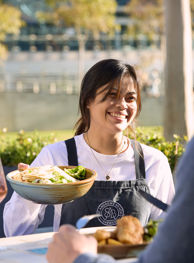 Waitress smiling and serving salad to guests at stadium food venue
